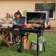Large charcoal barbecue grill with offset smoker box and side tables